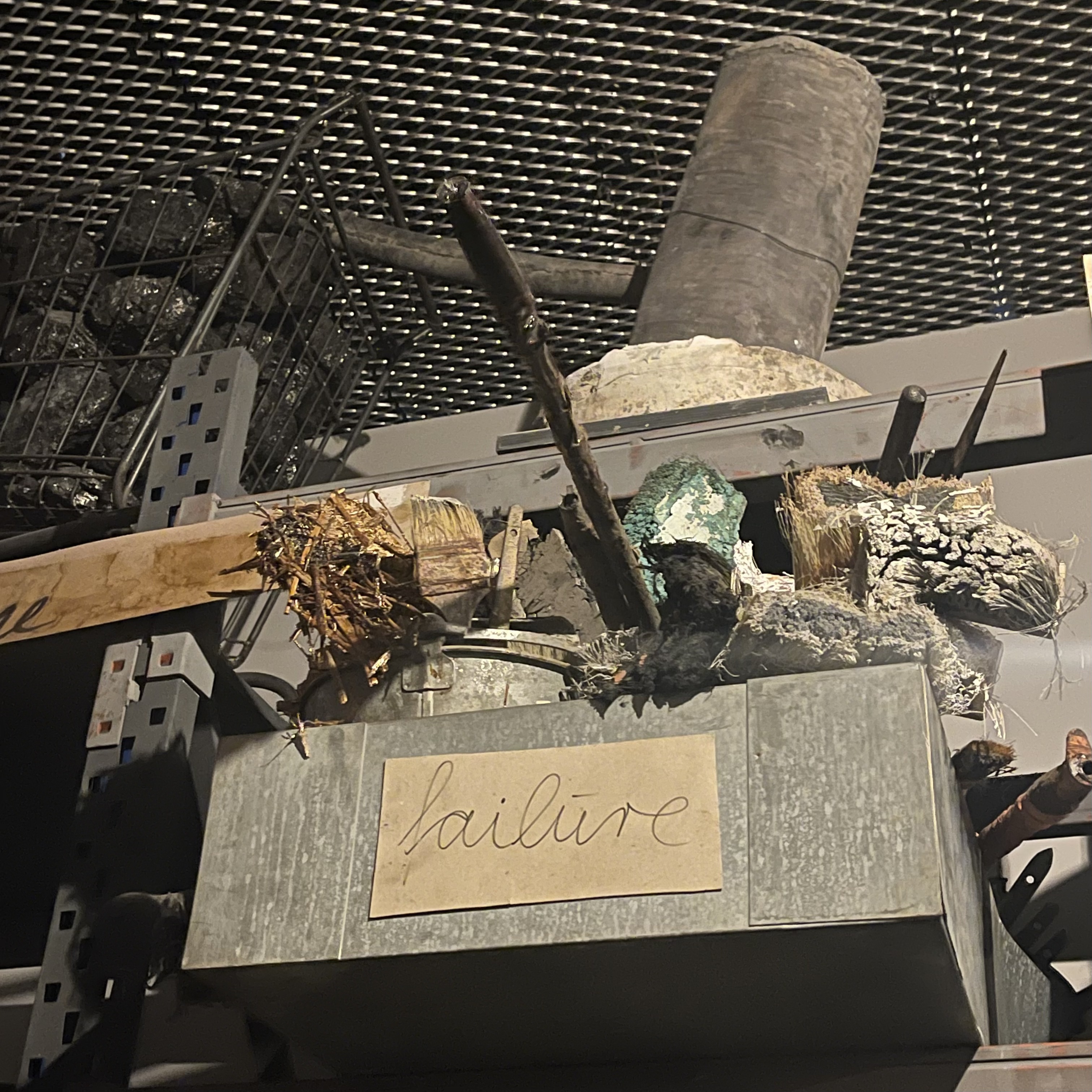 An installation in a Bermondsey gallery: a stack of scorched objects on a grey plinth labelled failure