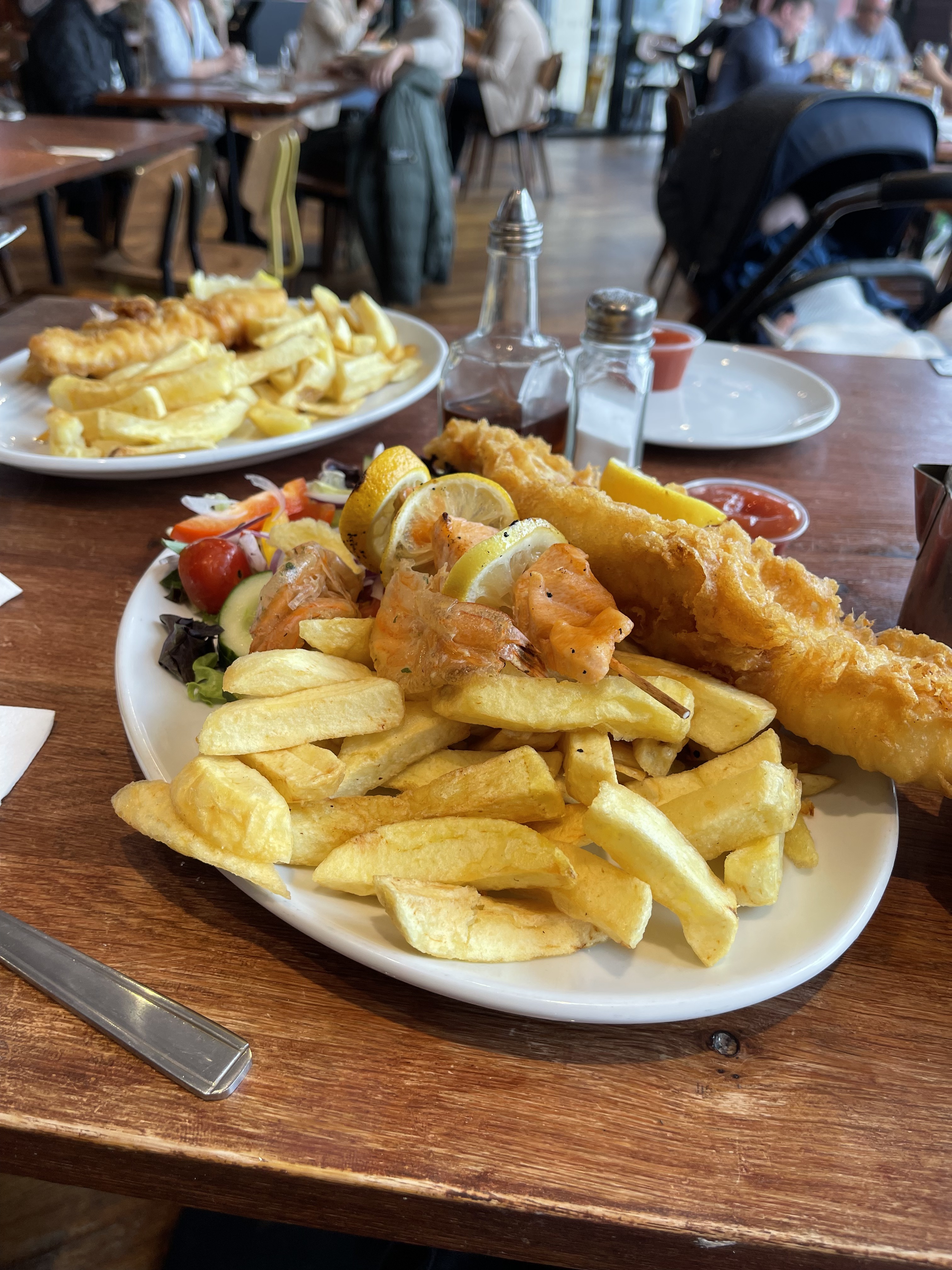 Two plates of fish and chips with salad on a wooden table in Blackpool