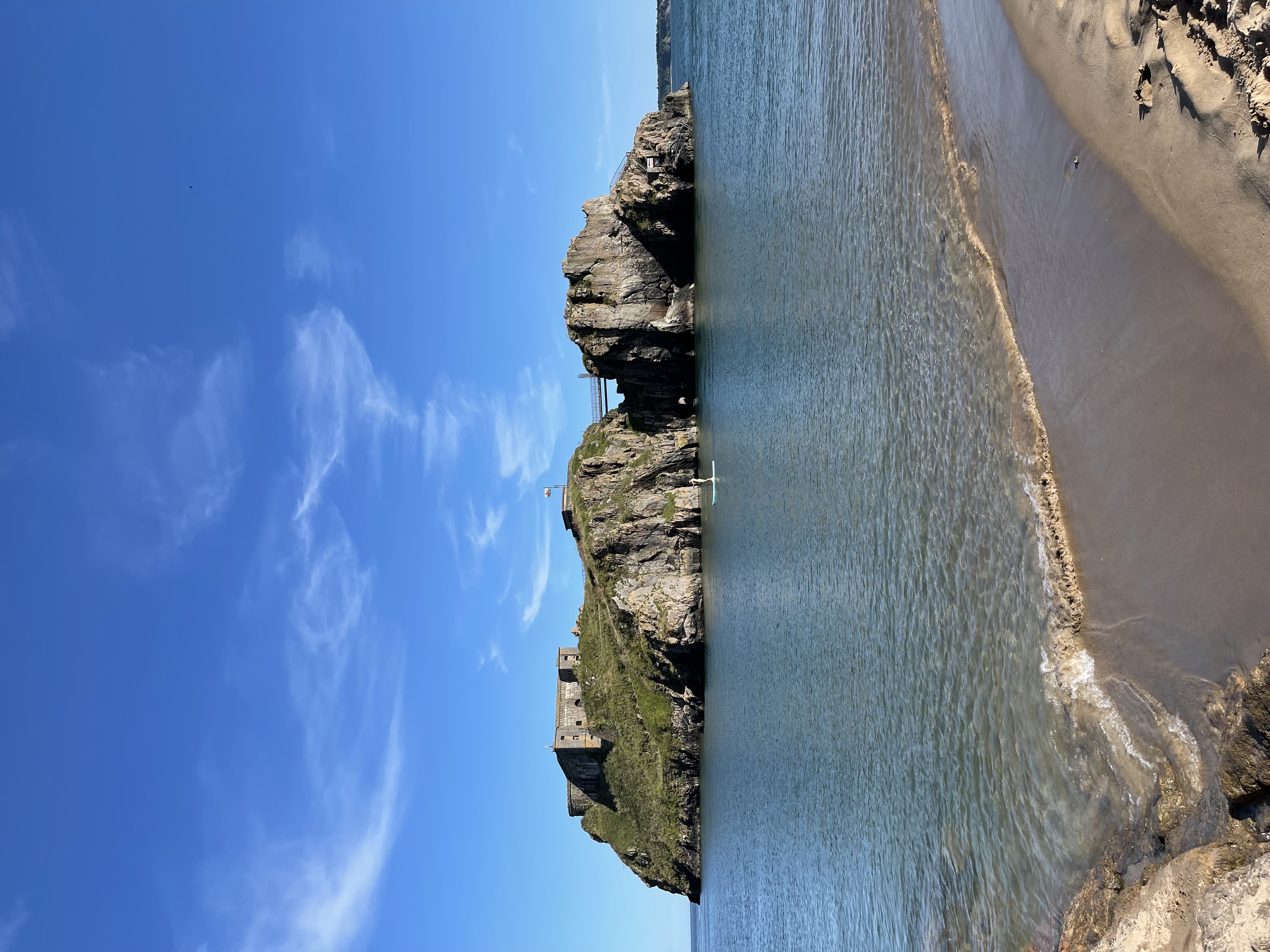St Catherine’s Island and its fort seen across the water from the beach at Tenby, under a blue sky