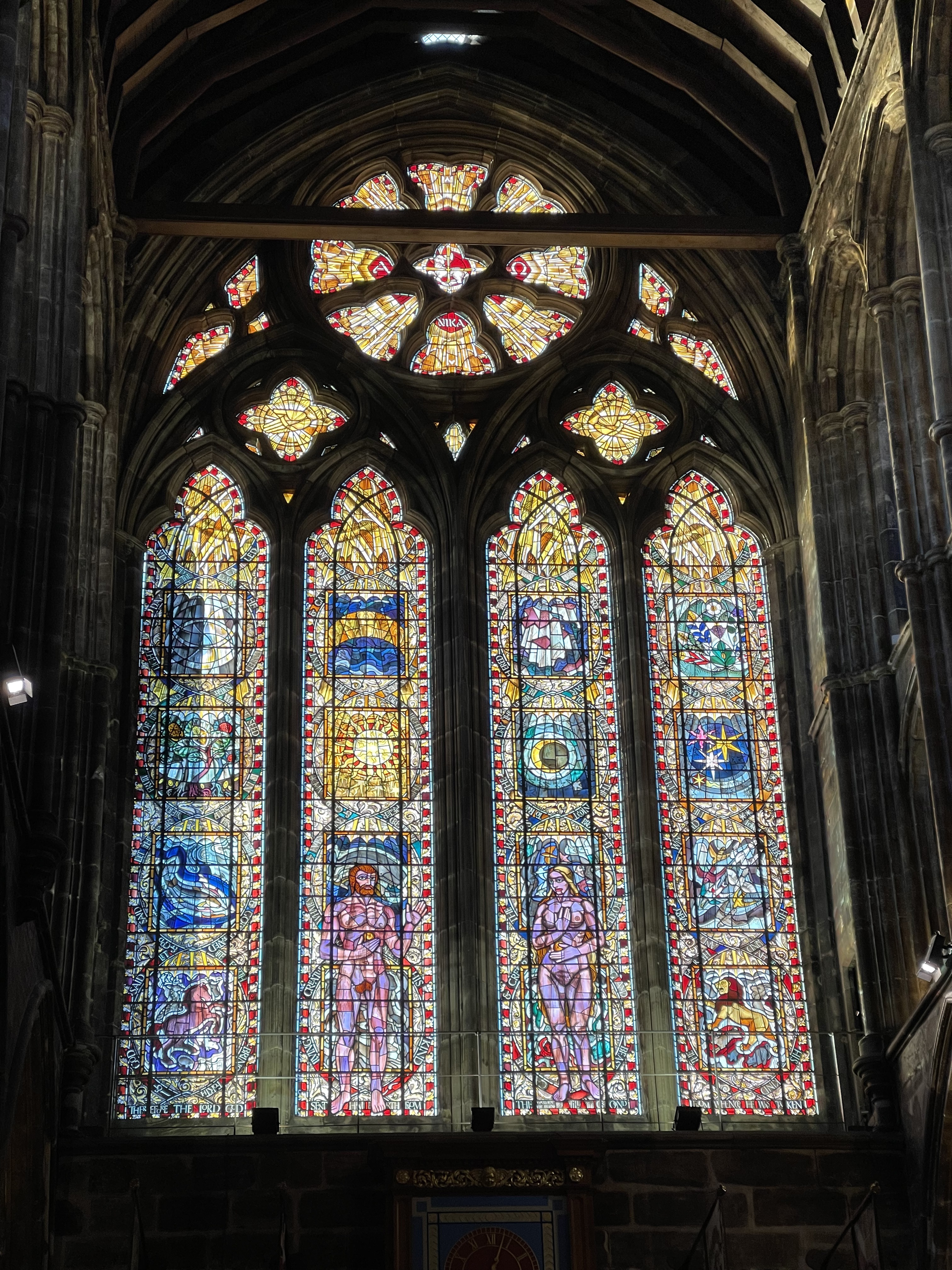 Tall stained glass windows glowing inside Glasgow Cathedral