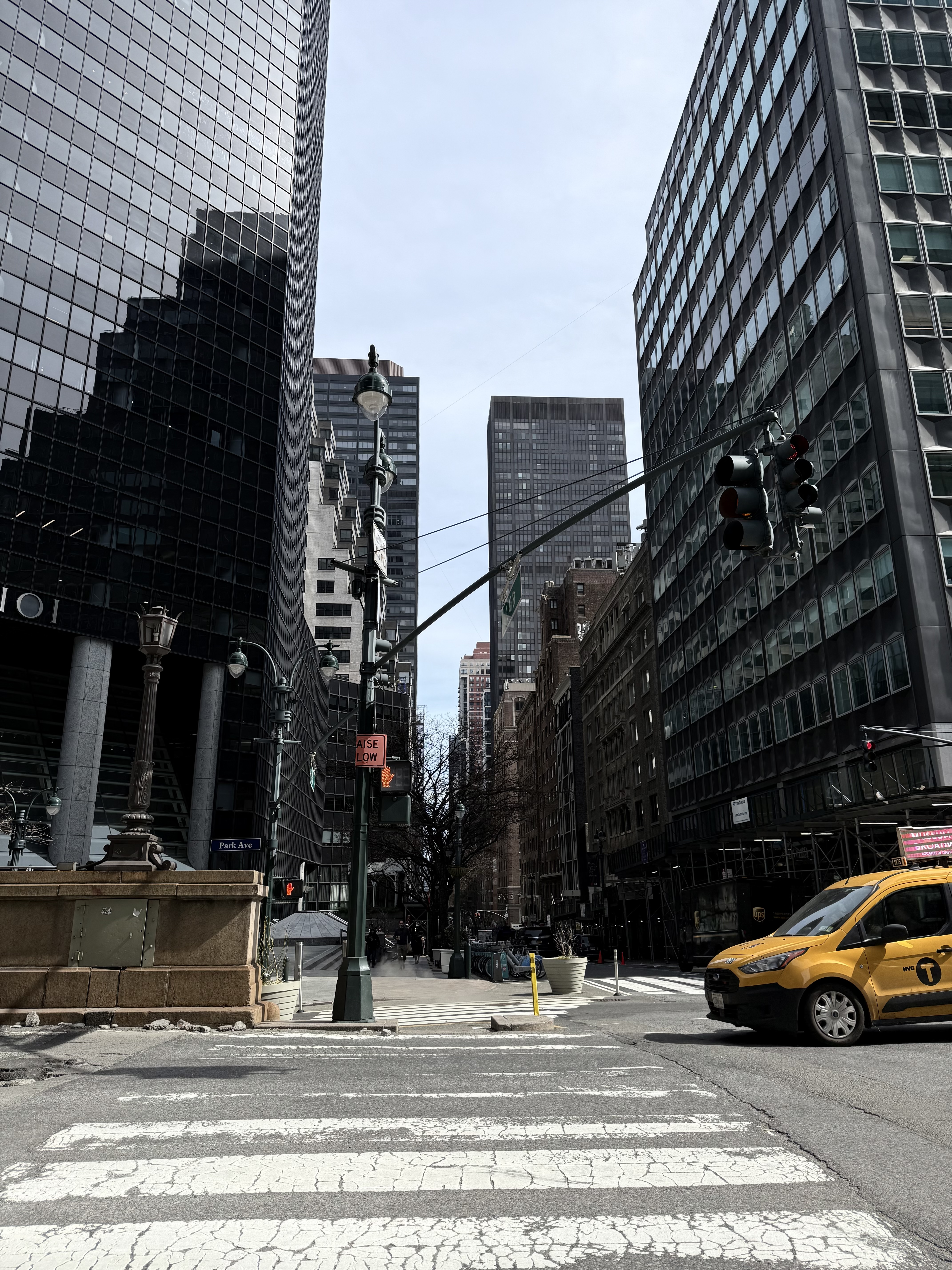 Office towers along Park Avenue in New York on a bright spring afternoon, with a yellow taxi at the crossing