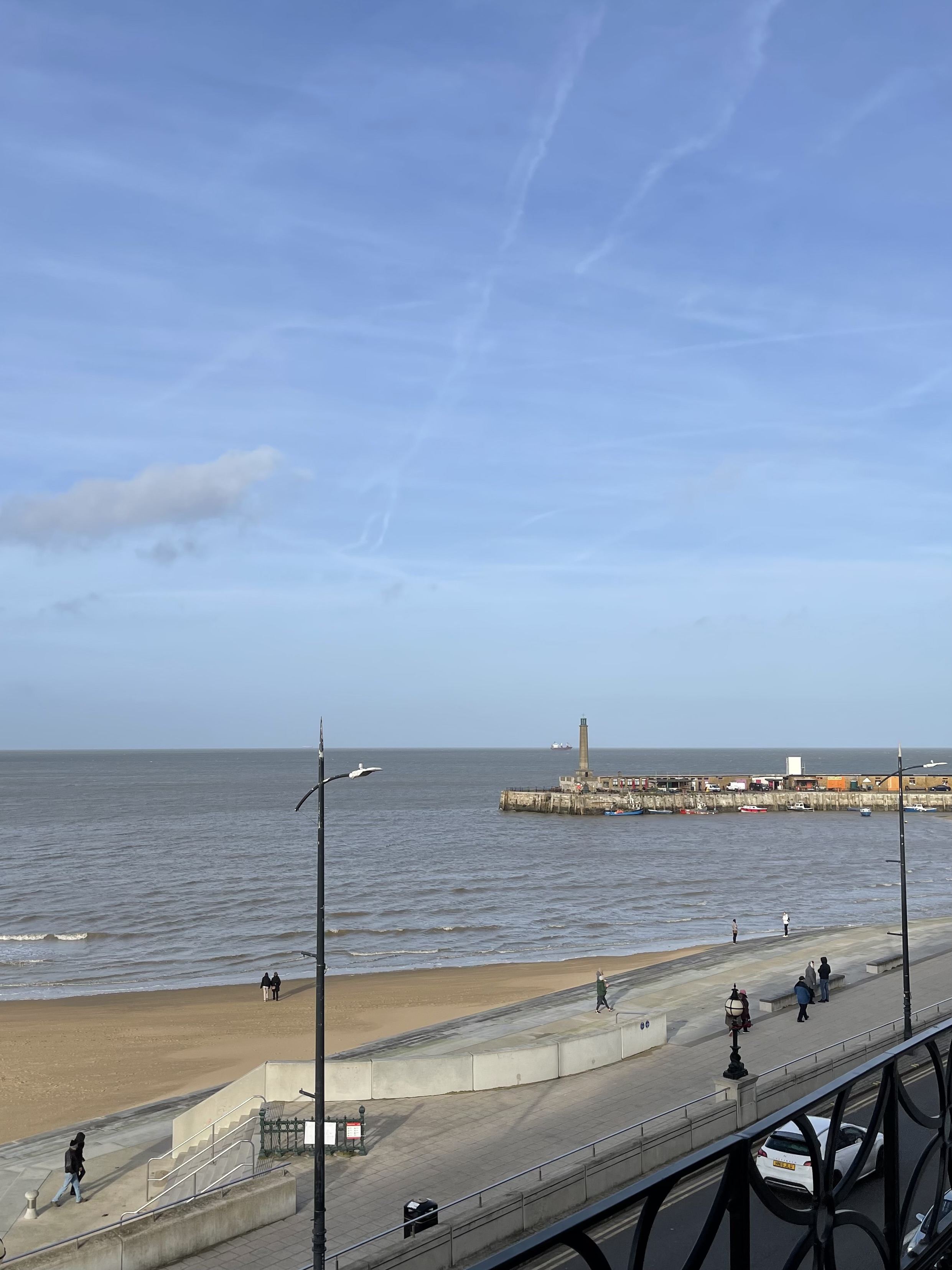 The seafront promenade and beach at Margate on a clear winter morning, with the harbour arm in the distance