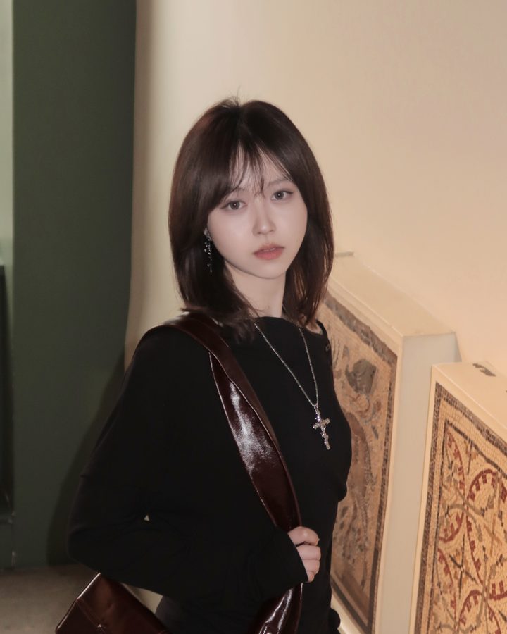 Portrait of Violet in a black dress on a museum staircase, beside framed mosaic panels